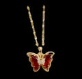 Butterfly-shaped pendant with red gemstones on a gold chain, displayed in a box.